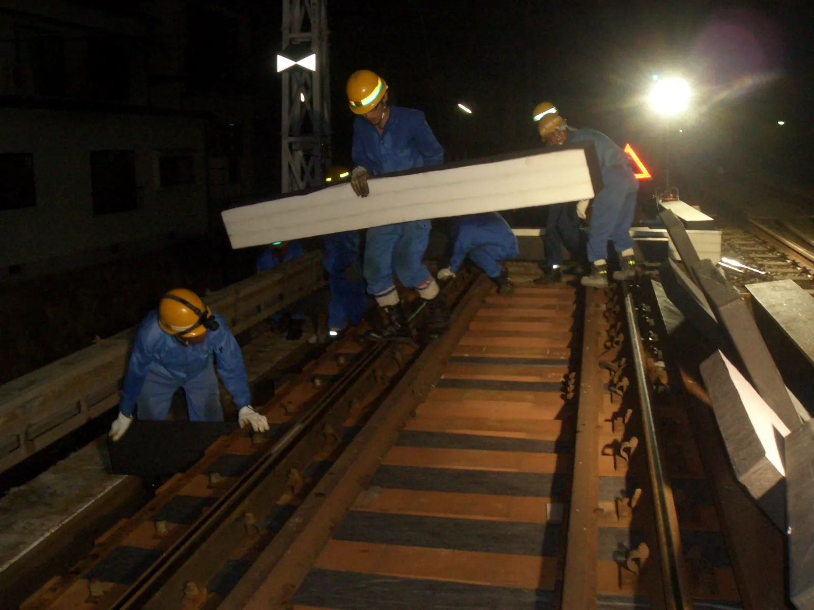 夜間に鉄道枕木間用吸音材を施工している様子